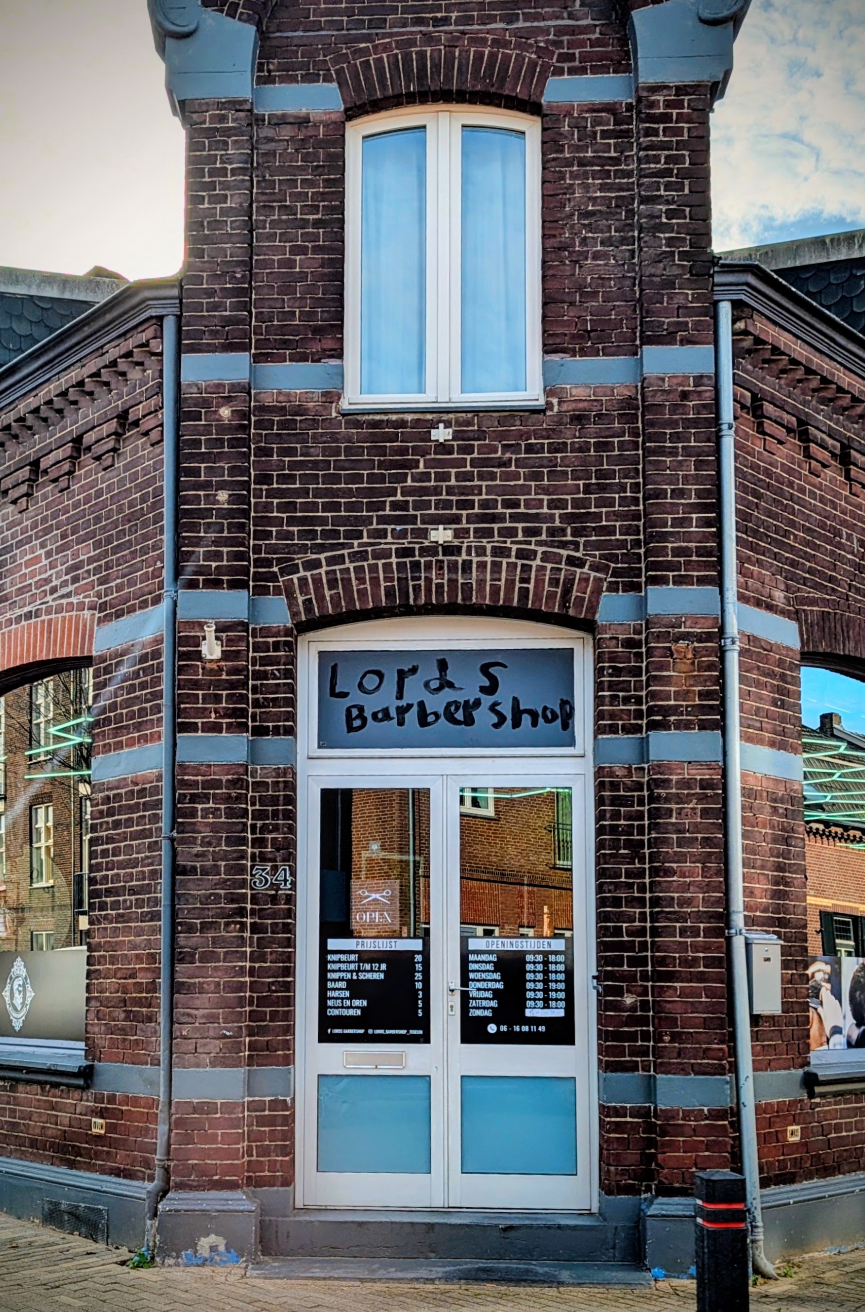 Het rode bakstenen hoekpand van Lords Barbershop, met 'Lord's Barbershop' op het glas boven de deur
